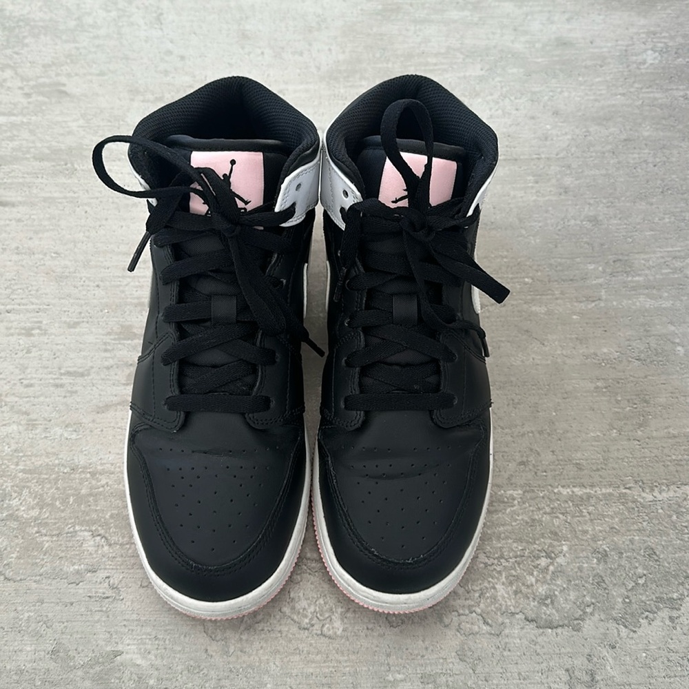 Air Jordan 1 Mids - black shoe, white sole, pink and white accents.